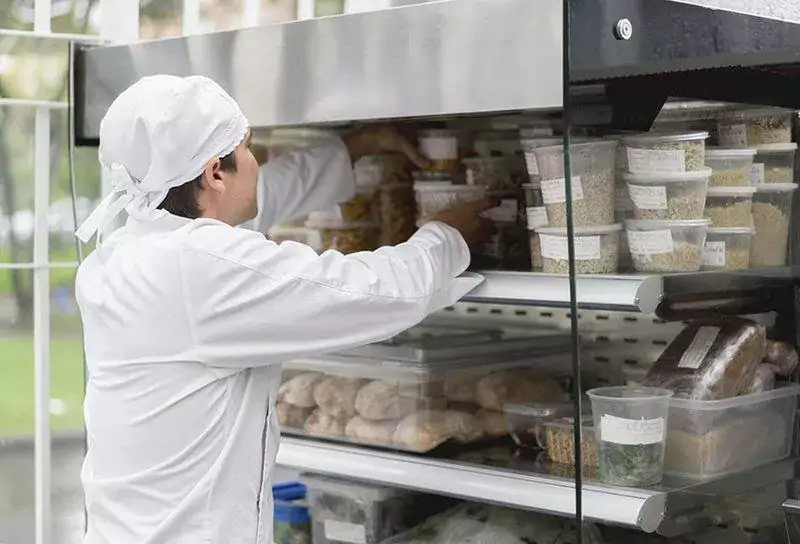 Employee grabbing food containers with food labels on them